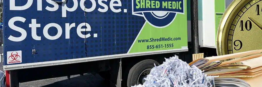 Composite image showing the side of a Shred Medic truck with the text "Dispose. Store." and a biohazard symbol, overlaid with a pile of shredded paper, a stack of file folders, and a large clock face in the foreground.